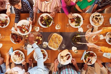 Overhead Shot Of Multi-Generation Family Sitting Around Table Enjoying Meal At Home Together - Powered by Adobe