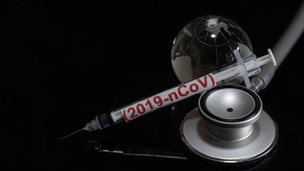 Syringe have text "(2019-nCoV)" and globe model and stethoscope  put on  Black background. corona virus Concept.