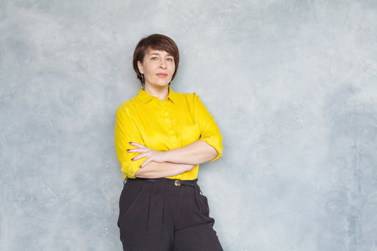 Confident Middle Aged Business Woman In Yellow Shirt On Gray Background