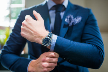 Guy in suit with a watch holding his sleeve