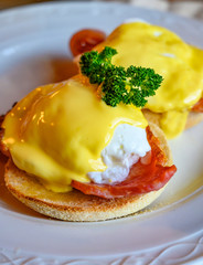 Weekend brunch in Scotland with two eggs benedict on homemade muffuns with roasted bacon and yellow hollandaise sauce.