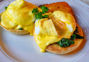 Weekend vegetarian brunch in Scotland with two eggs benedict on homemade muffuns with spinach and yellow hollandaise sauce.