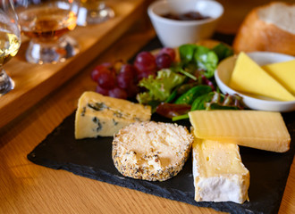 Tasting of original scottish cheese and whisky, plate with scottish cheeses and variety of Scotch in glasses