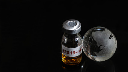 Vaccine bottle have  text "Corona virus" and  Globe model put on  Black background. corona virus Concept.