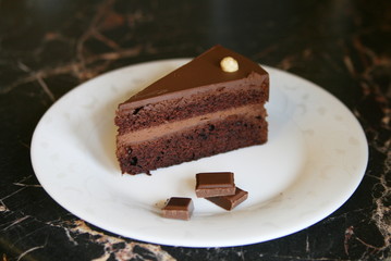 chocolate piece of cake with chocolate pieces on a white plate