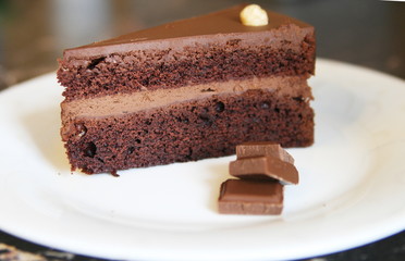 chocolate piece of cake with chocolate pieces on a white plate