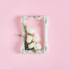 Creative composition of white rose flowers and frame. Pink background. Flowerscape flat lay.