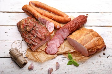Traditional smoked cold cuts on a paper and wooden boards. Classic meat products.