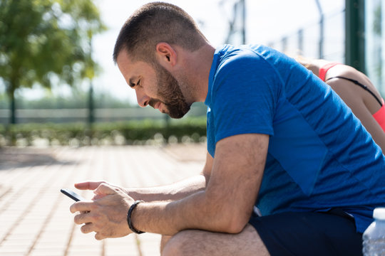 Profile Of A Man In A Tennis Court Using The Mobile