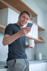 casual man with a Cup of coffee standing in the kitchen