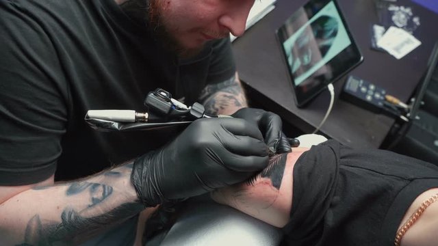 Shooting of professional getting tattoo of snake in studio