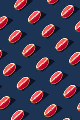 Flat lay pattern with summer grapefruit fruit on blue background. Minimal concept with sharp shadows. Trendy social mockup or wallpaper.