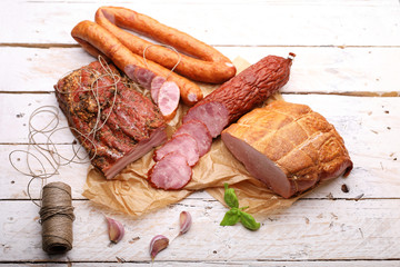 Composition of smoked cold cuts on a paper and wooden boards. Traditional meat products.
