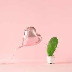 Heart shaped foil balloon with cactus plant and pink background. Creative Love or valentine concept.