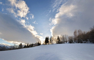 beautiful landscape of  mountain covered with snow  with cloudy sky and sunlight in the trees