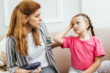 worried mother with ice bag compress talking to daughter with headache