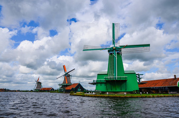 Zaanse Schans, Holland, August 2019. Northeast Amsterdam is a small community located on the Zaan River. View of the mills on the river bank, they stand out with their bright colors. Cloudy day.