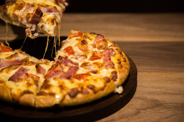 hot cheese piuzza in dinner light on wood table