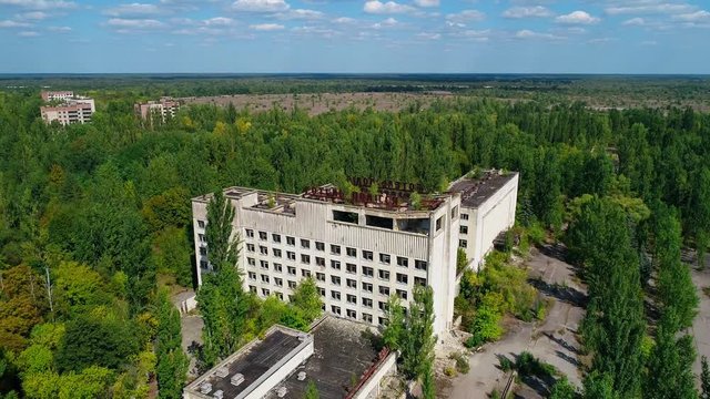 Aerial view of abandoned hotel and streets overgrown with trees in city Pripyat near Chernobyl nuclear power plant. Cyrillic inscription "Hotel Polissya". Exclusion Zone 4K drone footage