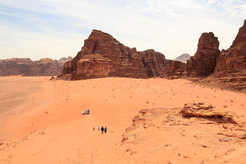 Fototapeta na wymiar Wadi Rum desert panorama with dunes, mountains, tourists and Pickup trucks, Jordan