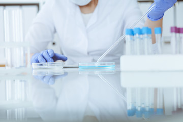 Close-up of professional female scientist in protective eyeglasses making experiment with reagents...