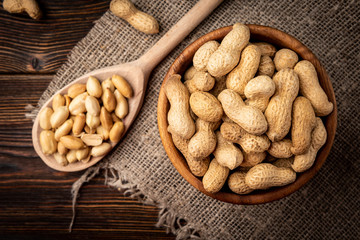 Peanut in the shell in wooden bowl on dark wooden background.