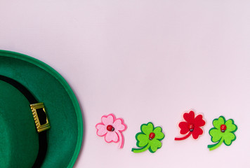March 17 is the feast of St. Patrick. Green felt hat and shiny paper clover leaves on a white...