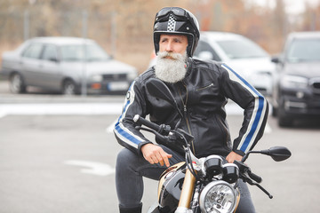 Fototapeta na wymiar Mature man riding a motorcycle. Old male on motorbike. Bearded man outdoors driving.