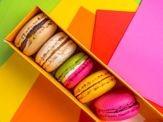 Colorful macaroons in box on festive colorful background