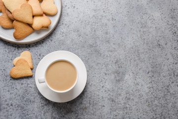 Valentines day greeting card with heart cookies and coffee cup on grey stone table.