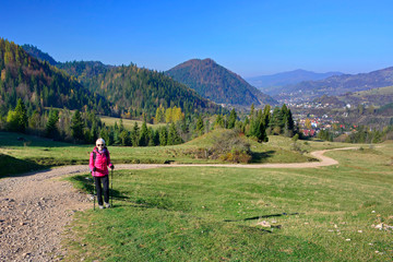 Fototapeta na wymiar Woman hiking in Pieniny Mountains on a footpath in sunny autumn day, Szczawnica, Poland