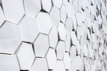 White geometric mosaics of a façade. Angles, six sides, hexagon, continuous, infinite, wall, sun...