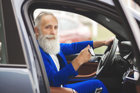 Old Handsome Man Inside The Car. Bearded Mature Male In The Automobile. Confident Businessman Buying The Car.