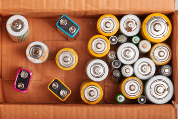 Discharged batteries in cardboard box. Collecting used batteries to recycle. Waste disposal and...