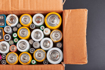 Discharged batteries in cardboard box. Collecting used batteries to recycle. Waste disposal and...