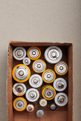 Discharged batteries in cardboard box. Collecting used batteries to recycle. Waste disposal and...