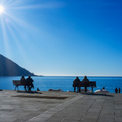 Tourists take a sunbath over the Camogli seafront (Ligurian Region, Northern Italy), during wintertime morning.