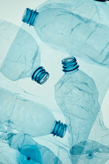 Empty plastic squashed bottles over blue background. Collecting plastic waste to recycling. Concept...