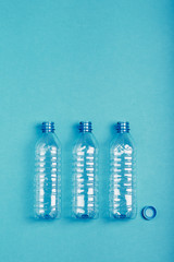 Empty plastic bottle, cup and cap over blue background. Collecting plastic waste to recycling. Concept of plastic pollution and too many plastic waste. Copy space at the top