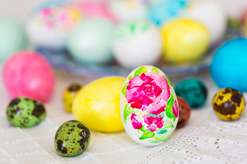 Colorful hand painted with watercolor easter eggs with painting of flowers on lace tablecloth
