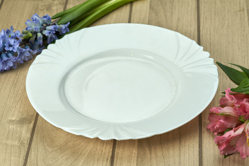 white plate on a wooden table flowers