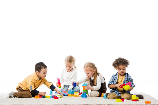 multicultural children playing with wooden blocks on carpet, isolated on white