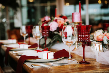 Romantic red table, decorated table with flowers and red candles. Luxury Christmas evening or wedding party decoration.