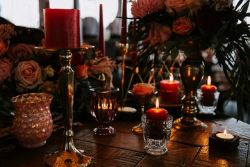 Romantic red table, decorated table with flowers and red candles. Luxury Christmas evening or wedding party decoration.