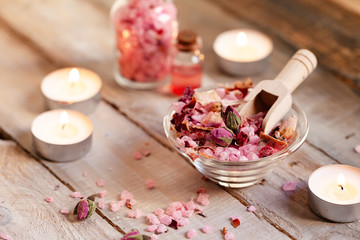 Concept of spa treatment with roses. Crystals of sea pink bath salt, candles as decor. Atmosphere of relax and pleasure. Anti-stress and detox procedure. Luxury lifestyle. Wooden background