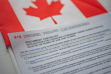 Document check list application for canadian citizenship next to Canadian flag, close up view.