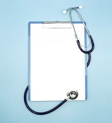 Flat lay of stethoscope and writing pad paper clip board on light blue background with copy space, healthcare and medical concept, top view photo.
