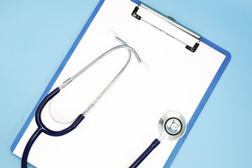Flat lay of stethoscope and writing pad paper clip board on light blue background with copy space, healthcare and medical concept, top view photo.