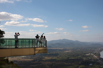 Travelers thai people travel visit and posing for take photo view of landscape of Nongkhai city and loas and Mekong river on glass skywalk of cliffs at Wat Pha Tak Suea temple in Nong Khai, Thailand