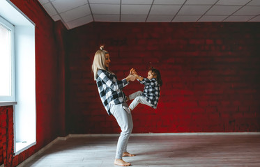 Young mother and her daughter doing exercises practicing yoga together at gym